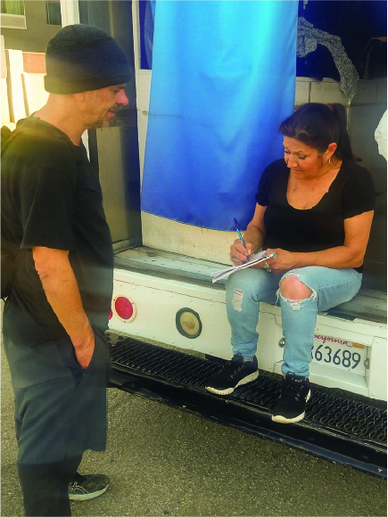 a man wearing a beanie and woman sitting on a vehicle while writing